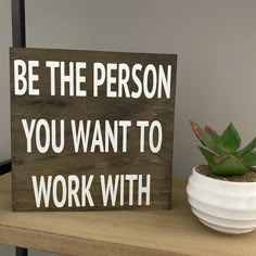 a wooden sign that says be the person you want to work with next to a potted plant