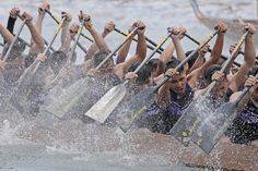 a group of people rowing on top of a lake with paddles in their hands