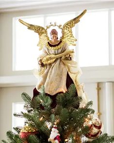 an angel figurine sitting on top of a christmas tree