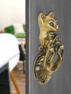 a door handle with a gold cat on it and a dragon in the middle is attached to a wooden door