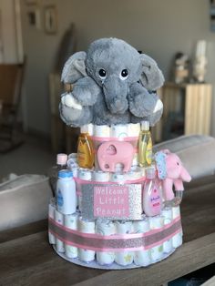 a stuffed elephant sitting on top of a diaper cake with baby items around it