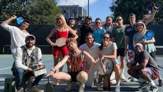 a group of people posing for a photo on a tennis court