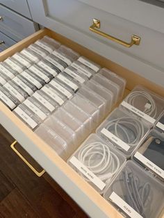 the drawers are filled with different types of cords and cables in plastic containers on top of wood flooring