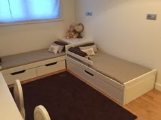 a room with two beds, drawers and a table in it that has a teddy bear on top