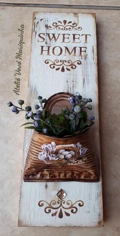 a wooden sign with flowers on it that says sweet home and is hanging on the wall