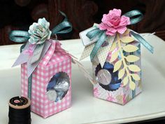 two small boxes with flowers on them are sitting next to a spool of thread