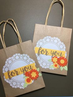 two brown paper bags with doily on them that say for you and flowers in the center