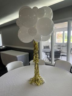 a table topped with white and gold balloons