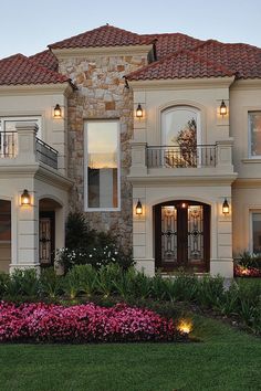 a large house with lots of windows and lights on it's front lawn area