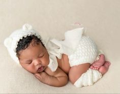 a newborn baby is wearing a white knitted hat and laying on it's side