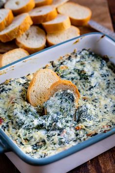 spinach dip in a blue casserole dish with slices of bread