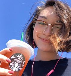 a woman wearing headphones and holding a drink