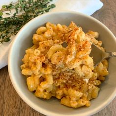 a white bowl filled with macaroni and cheese on top of a wooden table