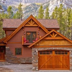 a brown house with two garages and mountains in the background