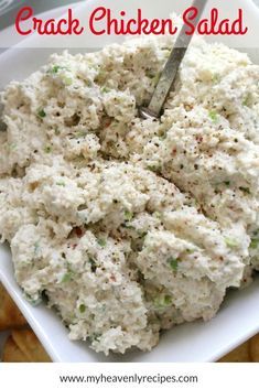 a white bowl filled with chicken salad next to crackers and a fork in it