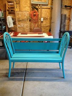 a blue bench sitting on top of a cement floor next to a wooden table and chair