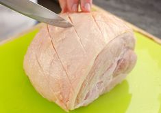 a person cutting up a piece of meat on a green cutting board with a knife