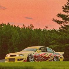 a yellow car parked on the side of a road next to some trees and grass