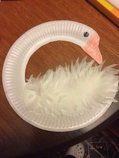 a paper plate that has a white swan on it and some feathers in the shape of a circle