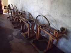 there are many old fashioned spinning wheels on the stand in front of the wall,