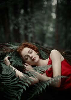 a woman in a red dress is laying on the ground with her eyes closed and hands behind her head