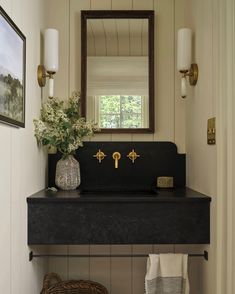 a bathroom sink sitting under a mirror next to a wall mounted faucet and a basket