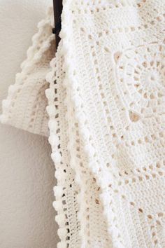 a white crocheted blanket hanging on a wall