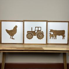 three framed farm animals and a tractor are on a wooden table next to a wall