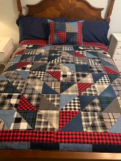 a bed with a plaid quilt and pillows on it