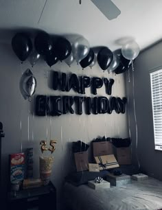 a room filled with balloons and boxes on top of a bed next to a window