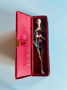 an open red box with a doll in it