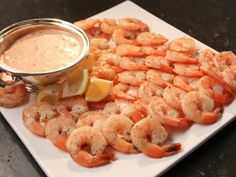 a white plate topped with shrimp next to a dipping sauce