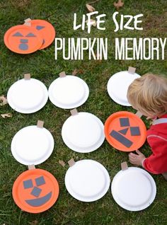 a little boy playing with paper plates and pumpkins on the grass in front of him