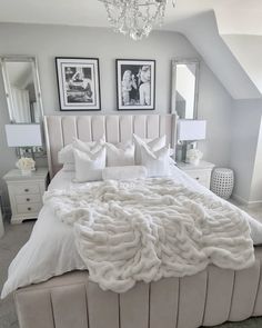 a bed with white sheets and pillows in a bedroom next to two pictures on the wall