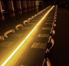 rows of benches lined up in front of a building with yellow lights shining down on them