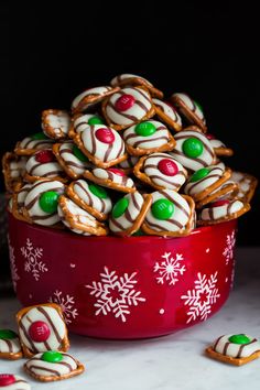 a red bowl filled with white and green candy covered pretzel cookies next to other holiday treats