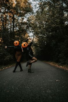 two people dressed up as jack - o'- lanterns are dancing on the road