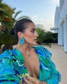 a woman in a blue and green dress with large earrings