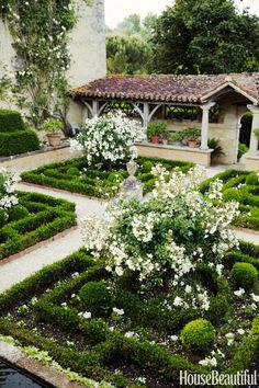 a garden with hedges and white flowers in it