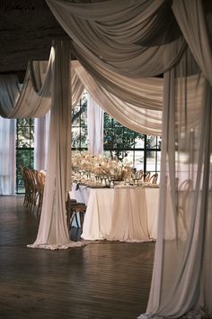 an image of a dining room setting with white drapes on the ceiling and table