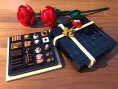 a lego box with chocolates and roses sitting on a table next to each other