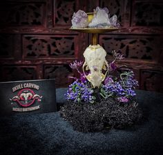 a skull sitting on top of a table next to some purple flowers and a book