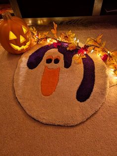 a halloween door mat with a ghost face on it and pumpkins in the background