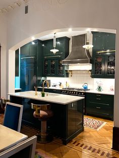 a kitchen with dark green cabinets and white counter tops is seen through an archway in the center of the room