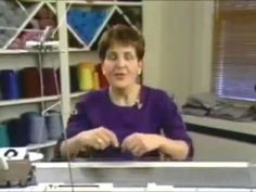 a woman sitting at a sewing machine in front of a shelf with yarn on it