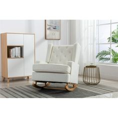 a white rocking chair sitting on top of a rug next to a book shelf and window