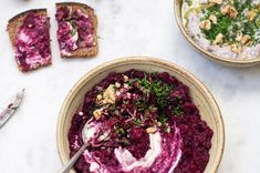 two bowls filled with beet hummus, toasted bread and garnish