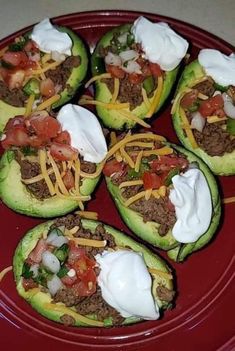 several stuffed avocados with cheese and other toppings on a red platter