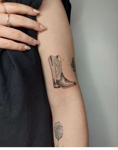 a woman's arm with a tattoo on it that has a boot and flower