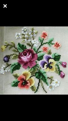 a cross stitch pattern with flowers and leaves on white fabric, in the shape of a flower bouquet